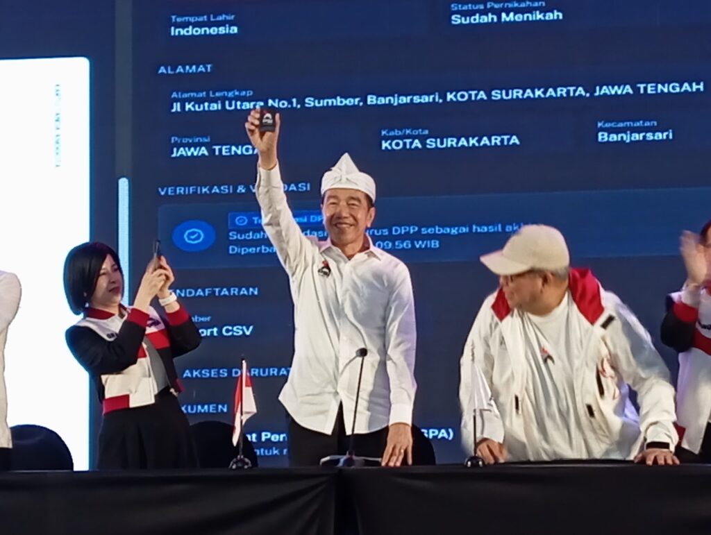 Joko Widodo (Jokowi) mengangkat kartu tanda anggota (KTA) Partai Solidaritas Indonesia (PSI)